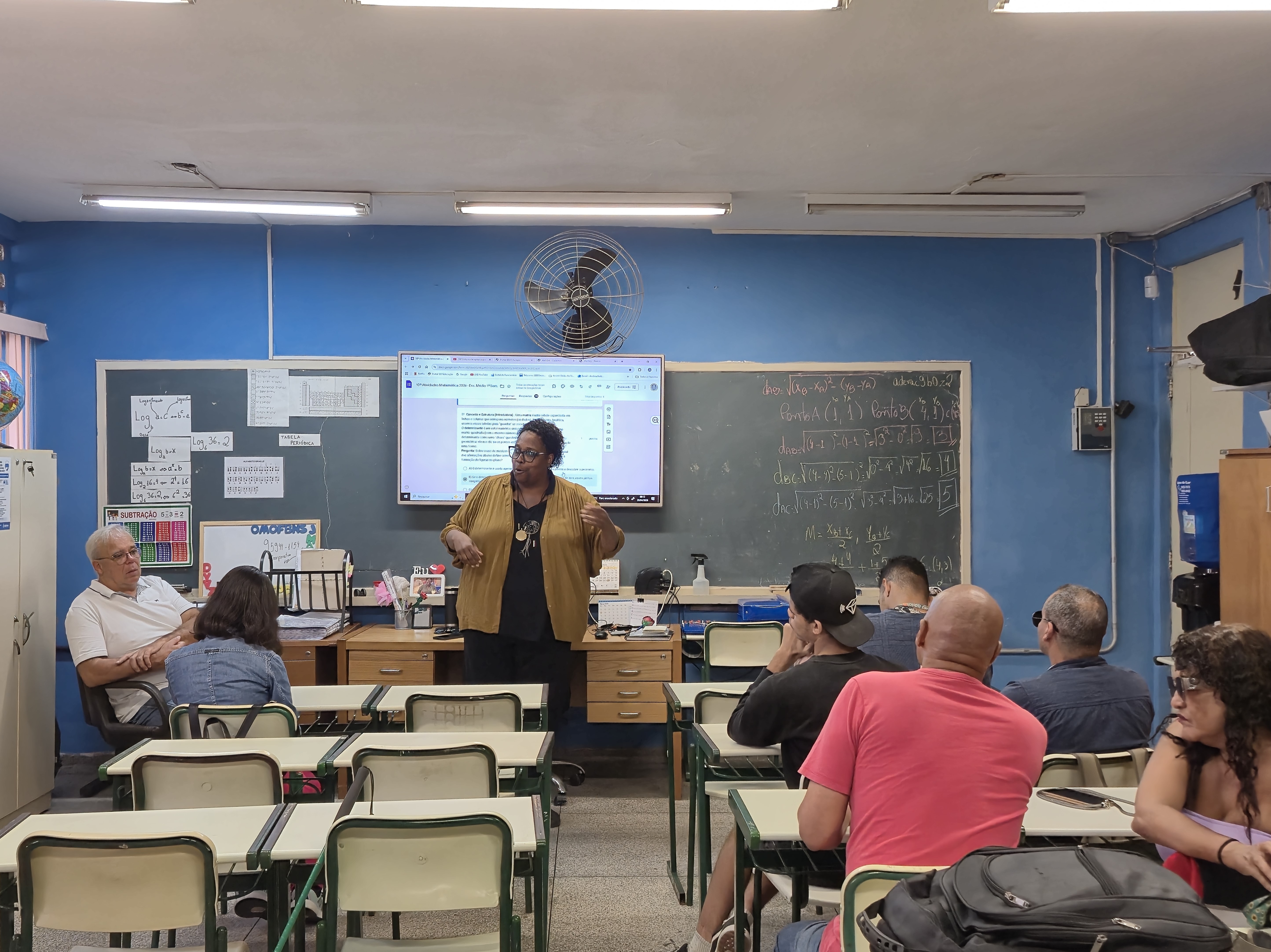 Instrutora ministrando aula teórica para alunos em uma sala de aula