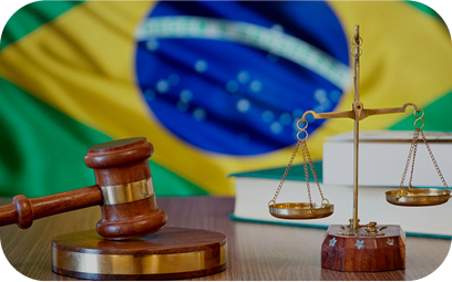 Martelo e balança da justiça sobre mesa com a bandeira do Brasil ao fundo.